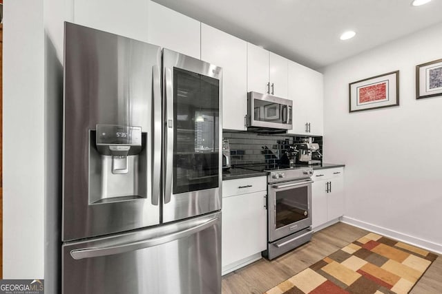 kitchen with decorative backsplash, white cabinetry, appliances with stainless steel finishes, and light hardwood / wood-style flooring