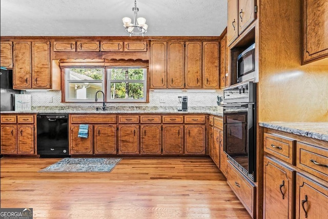 kitchen with light hardwood / wood-style flooring, backsplash, black appliances, pendant lighting, and a chandelier