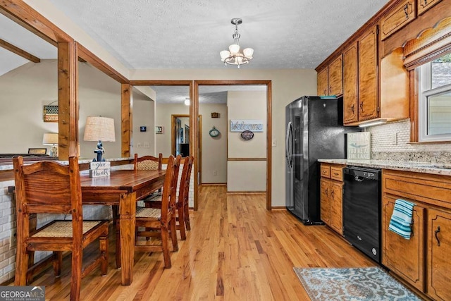 kitchen with black appliances, decorative light fixtures, a chandelier, a textured ceiling, and light hardwood / wood-style floors