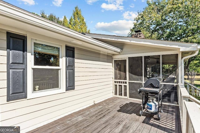 wooden terrace featuring a sunroom and a grill