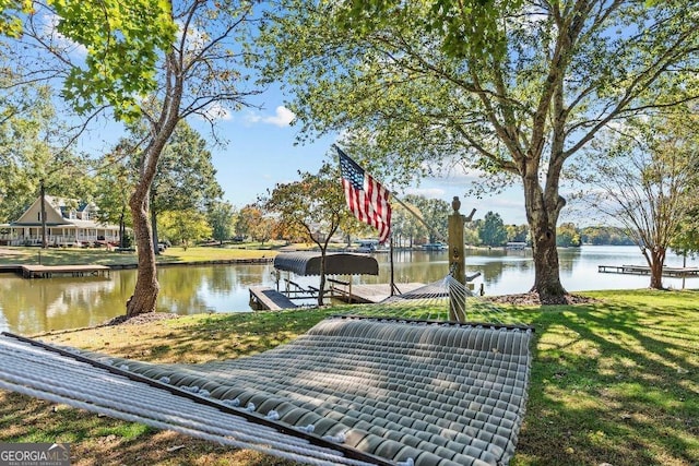 surrounding community featuring a boat dock, a yard, and a water view