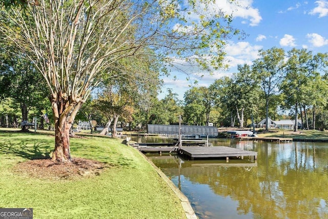 view of dock with a lawn and a water view