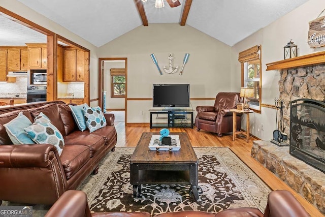 living room with light hardwood / wood-style floors, lofted ceiling with beams, a fireplace, and ceiling fan