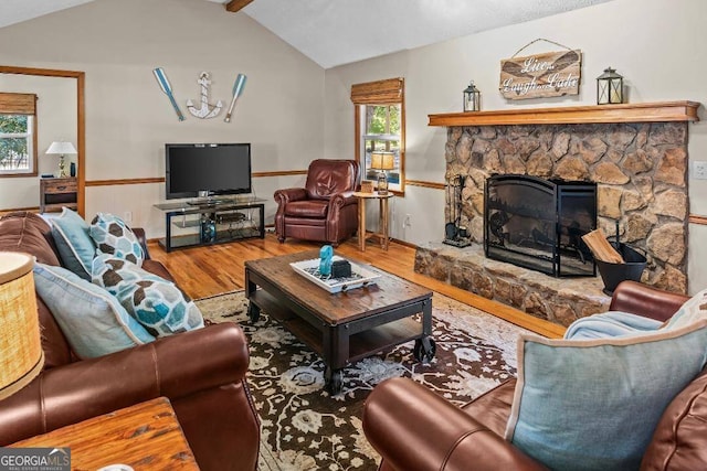 living room featuring lofted ceiling, hardwood / wood-style floors, a stone fireplace, and a healthy amount of sunlight