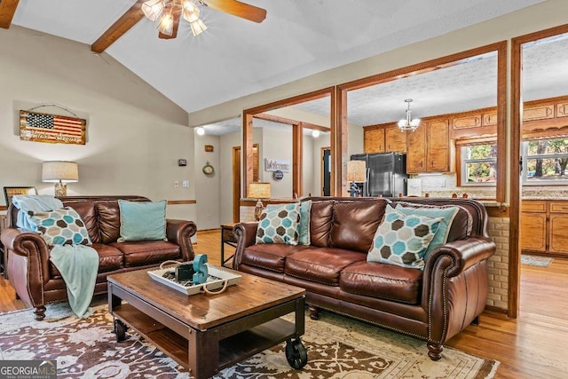 living room featuring vaulted ceiling with beams, ceiling fan with notable chandelier, and light hardwood / wood-style floors