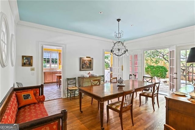 dining area with french doors, an inviting chandelier, crown molding, and wood-type flooring