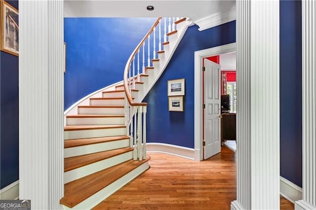 stairs featuring ornamental molding and hardwood / wood-style flooring