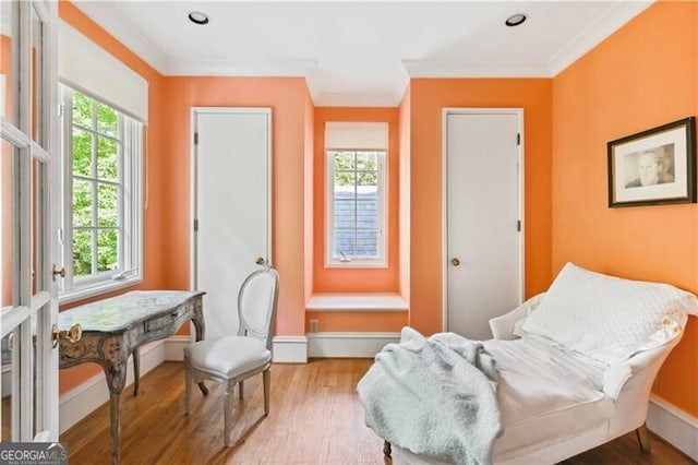 living area featuring hardwood / wood-style flooring, a wealth of natural light, and crown molding