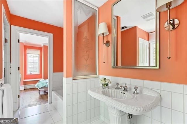 bathroom with tile patterned floors, a bathing tub, and sink