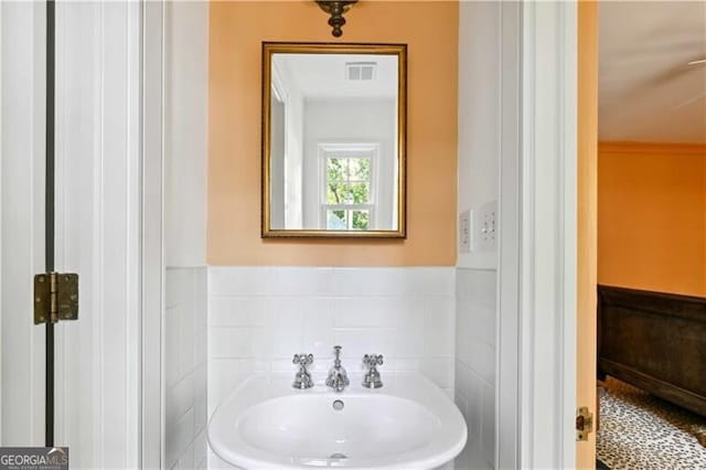 bathroom featuring sink and tile walls