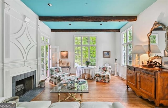 living area featuring a fireplace, hardwood / wood-style floors, a wealth of natural light, and beam ceiling