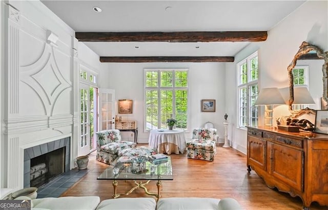 sitting room with a fireplace, hardwood / wood-style flooring, a wealth of natural light, and beamed ceiling