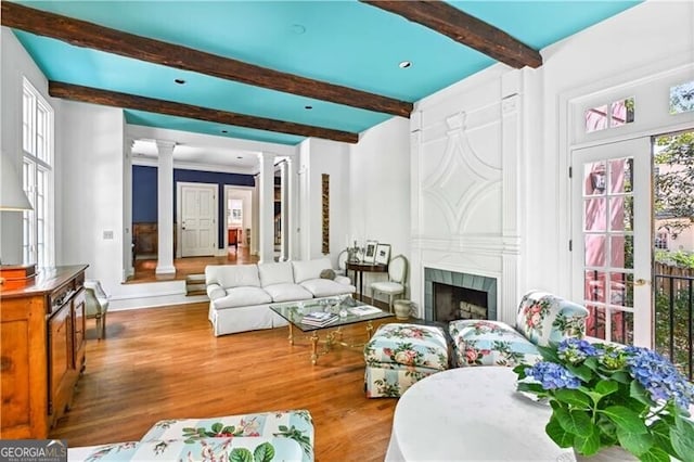 living room with french doors, decorative columns, a fireplace, beamed ceiling, and hardwood / wood-style floors