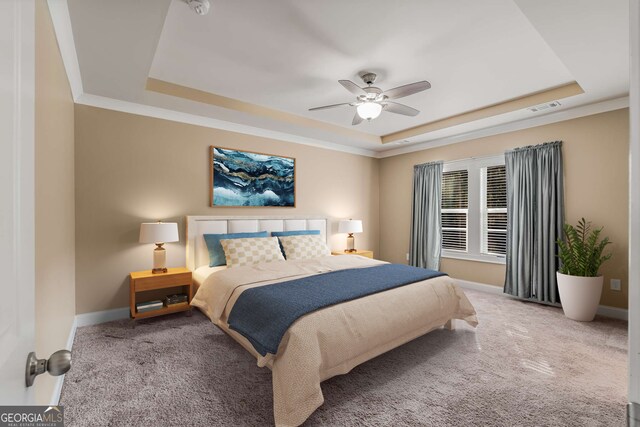 carpeted bedroom with ornamental molding, ceiling fan, and a raised ceiling