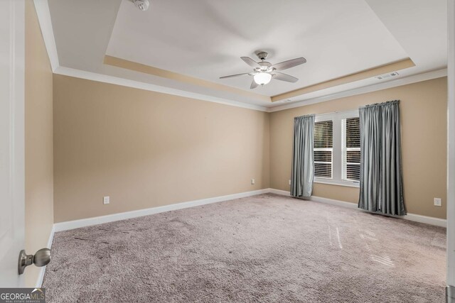 carpeted empty room featuring ornamental molding, a tray ceiling, and ceiling fan