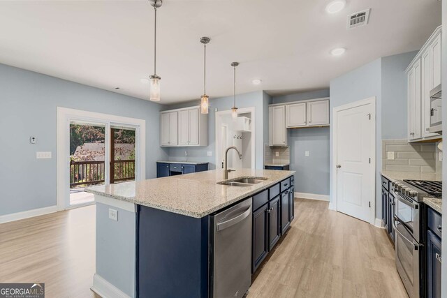 kitchen featuring white cabinetry, a kitchen island with sink, sink, and pendant lighting