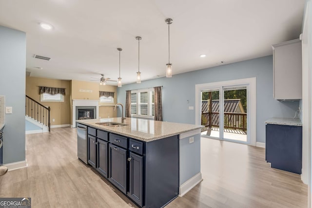 kitchen featuring light hardwood / wood-style flooring, decorative light fixtures, sink, and a center island with sink