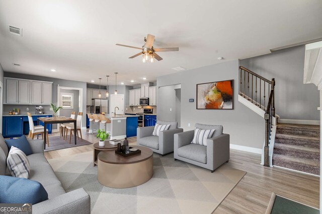 living room with light hardwood / wood-style flooring, sink, and ceiling fan