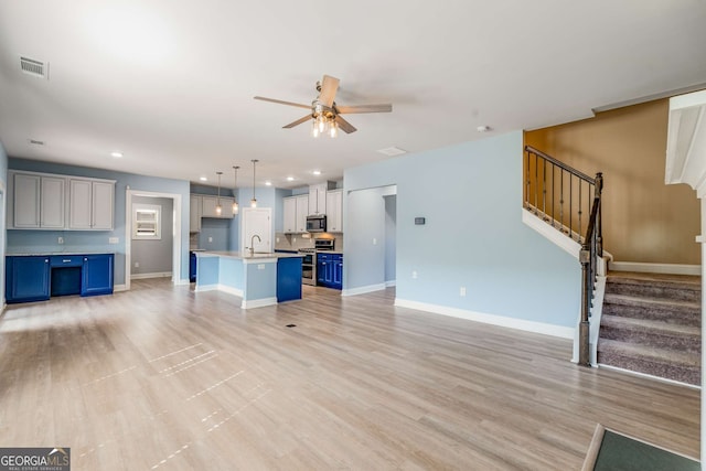 unfurnished living room with light hardwood / wood-style floors, sink, and ceiling fan