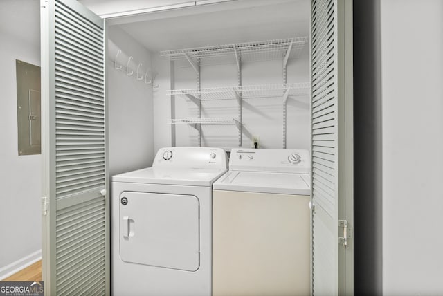 laundry room featuring electric panel, light hardwood / wood-style flooring, and washer and dryer