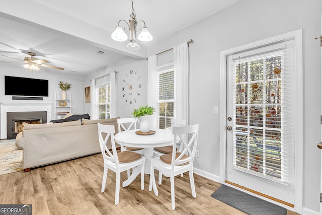 dining space with ceiling fan with notable chandelier, light hardwood / wood-style flooring, and a wealth of natural light