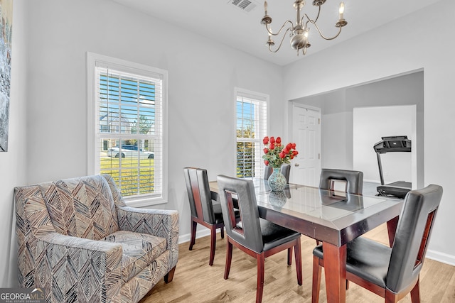 dining room with light hardwood / wood-style floors and an inviting chandelier