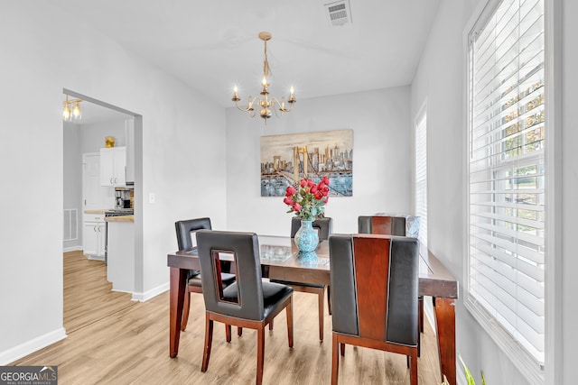 dining room with light wood-type flooring and a notable chandelier