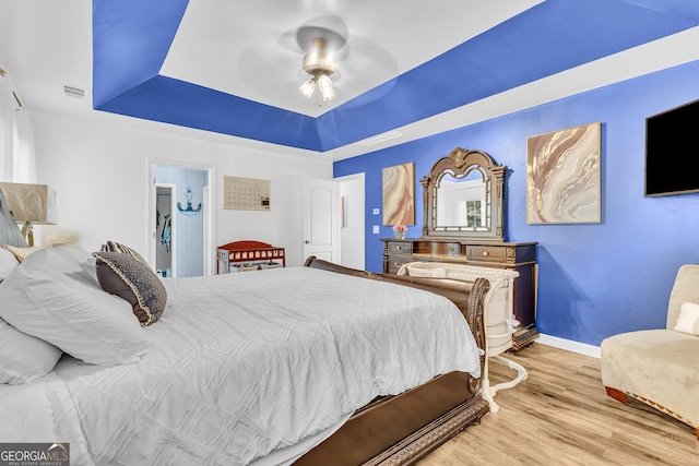 bedroom featuring a tray ceiling, ceiling fan, hardwood / wood-style floors, and a spacious closet