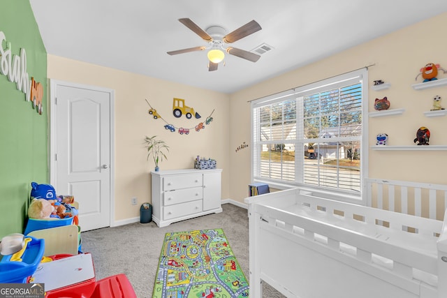 carpeted bedroom with ceiling fan and a nursery area