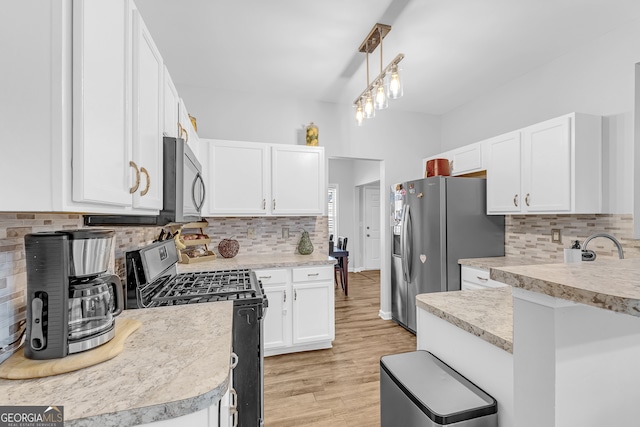 kitchen featuring light wood-type flooring, tasteful backsplash, stainless steel appliances, white cabinets, and hanging light fixtures