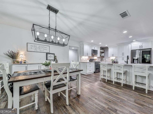 dining area featuring sink, dark wood-type flooring, and a chandelier