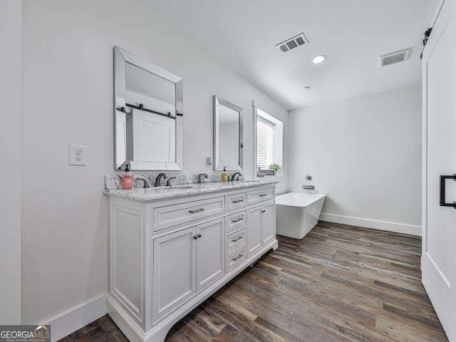 bathroom featuring vanity, wood-type flooring, and a tub to relax in