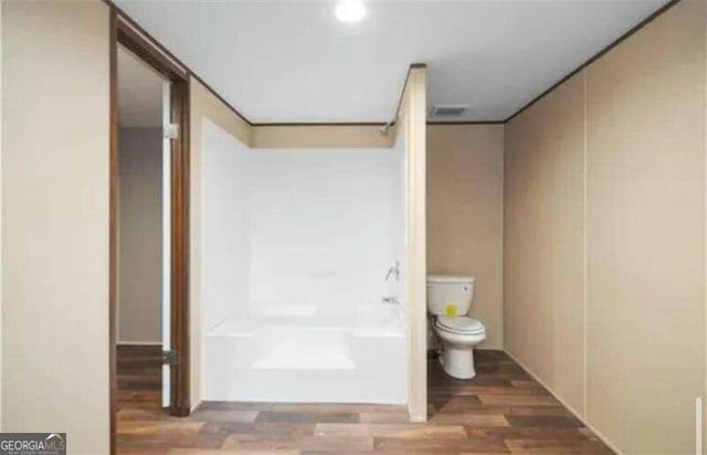 bathroom featuring toilet, wood-type flooring, and tub / shower combination