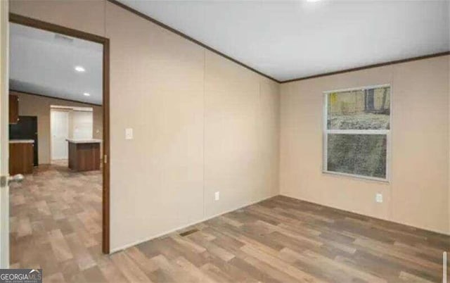 spare room with ornamental molding, lofted ceiling, and hardwood / wood-style floors