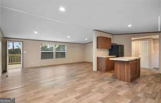 kitchen featuring light hardwood / wood-style floors, a center island, and black refrigerator