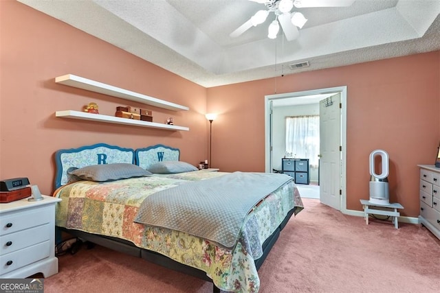 bedroom featuring light carpet, ceiling fan, and a tray ceiling