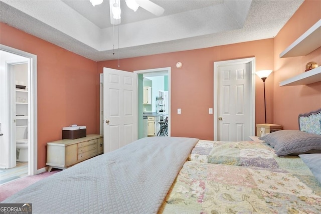 bedroom featuring carpet, a textured ceiling, a raised ceiling, ceiling fan, and ensuite bathroom