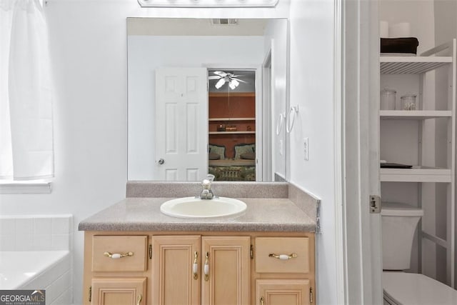 bathroom featuring a tub, ceiling fan, vanity, and toilet