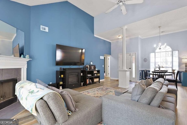 living room featuring a tile fireplace, light wood-type flooring, and high vaulted ceiling