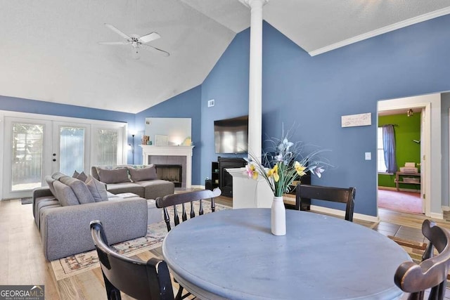 dining area with high vaulted ceiling, light wood-type flooring, ceiling fan, and a fireplace