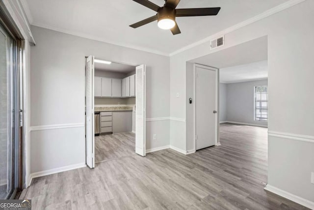 unfurnished living room with light hardwood / wood-style floors, ornamental molding, and ceiling fan