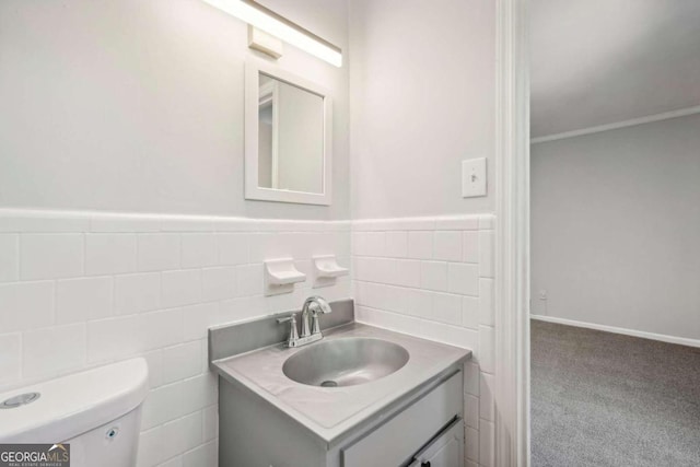 bathroom with vanity, toilet, tile walls, and ornamental molding