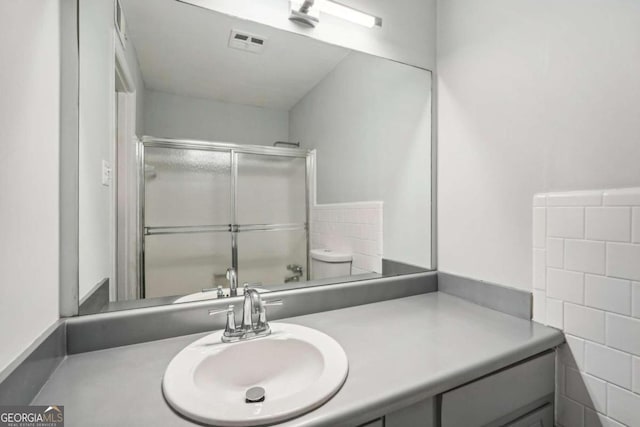 bathroom featuring vanity, tasteful backsplash, toilet, and walk in shower