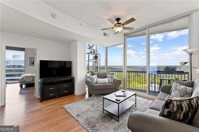 living room with light hardwood / wood-style floors, floor to ceiling windows, and ceiling fan