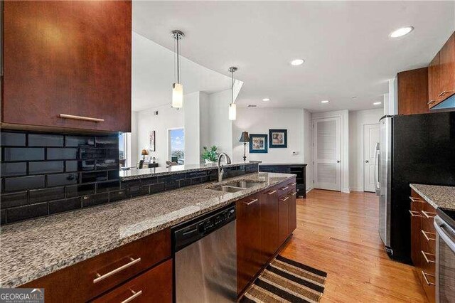 kitchen featuring light hardwood / wood-style flooring, backsplash, sink, light stone countertops, and appliances with stainless steel finishes