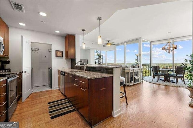 kitchen with light hardwood / wood-style floors, stainless steel appliances, kitchen peninsula, and a kitchen breakfast bar