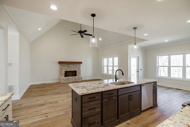 kitchen featuring dishwasher, dark brown cabinetry, light stone counters, sink, and a brick fireplace