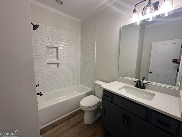 full bathroom featuring tiled shower / bath combo, vanity, wood-type flooring, ornamental molding, and toilet