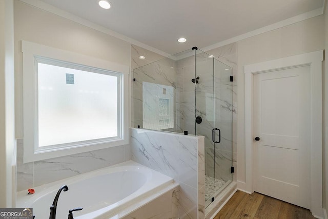 bathroom featuring separate shower and tub, hardwood / wood-style flooring, and ornamental molding