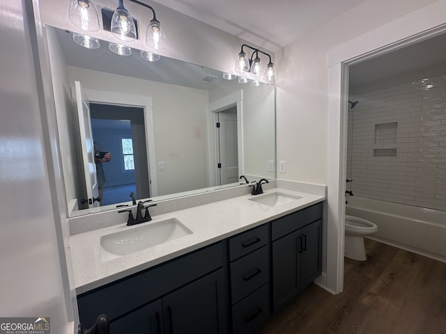 full bathroom with hardwood / wood-style flooring, vanity, tiled shower / bath, and toilet